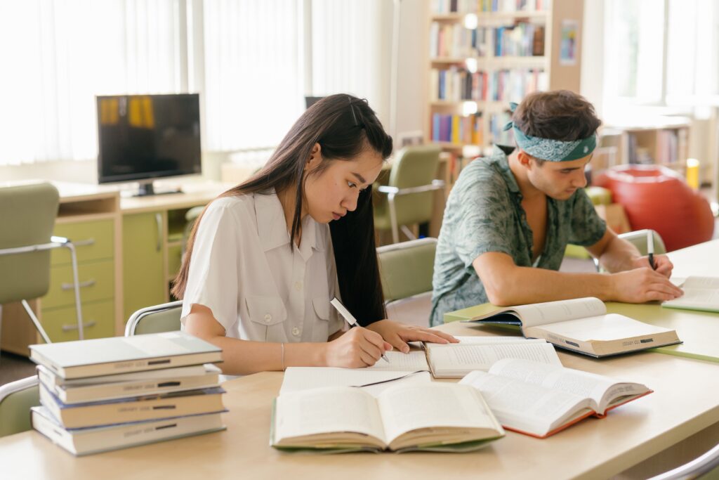 Two high school students focused on their studies together at a table in a modern school library in the Netherlands.